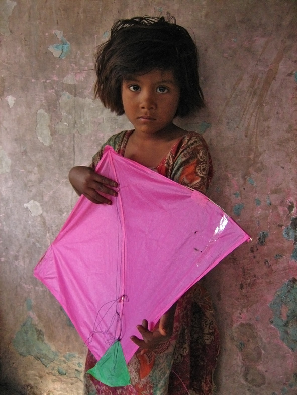 A child holding a kite at an Uttarayan gathering in Ahmedabad; an archival festival photograph