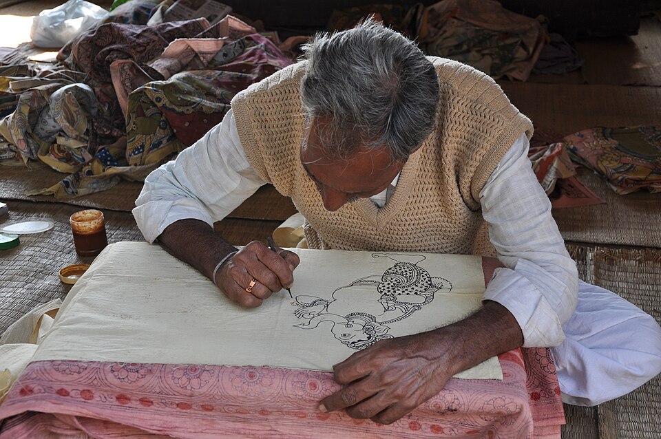 An artist drawing a Kalamkari composition