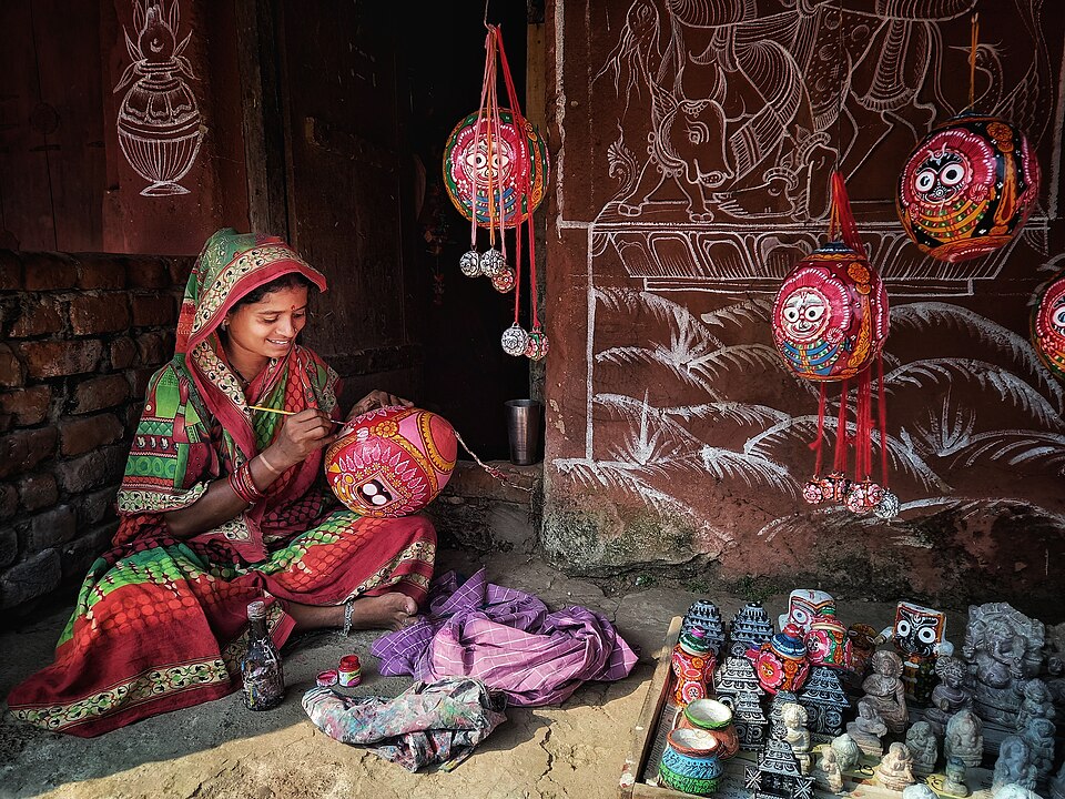 A Pattachitra artist at work in Odisha, with painted objects on display